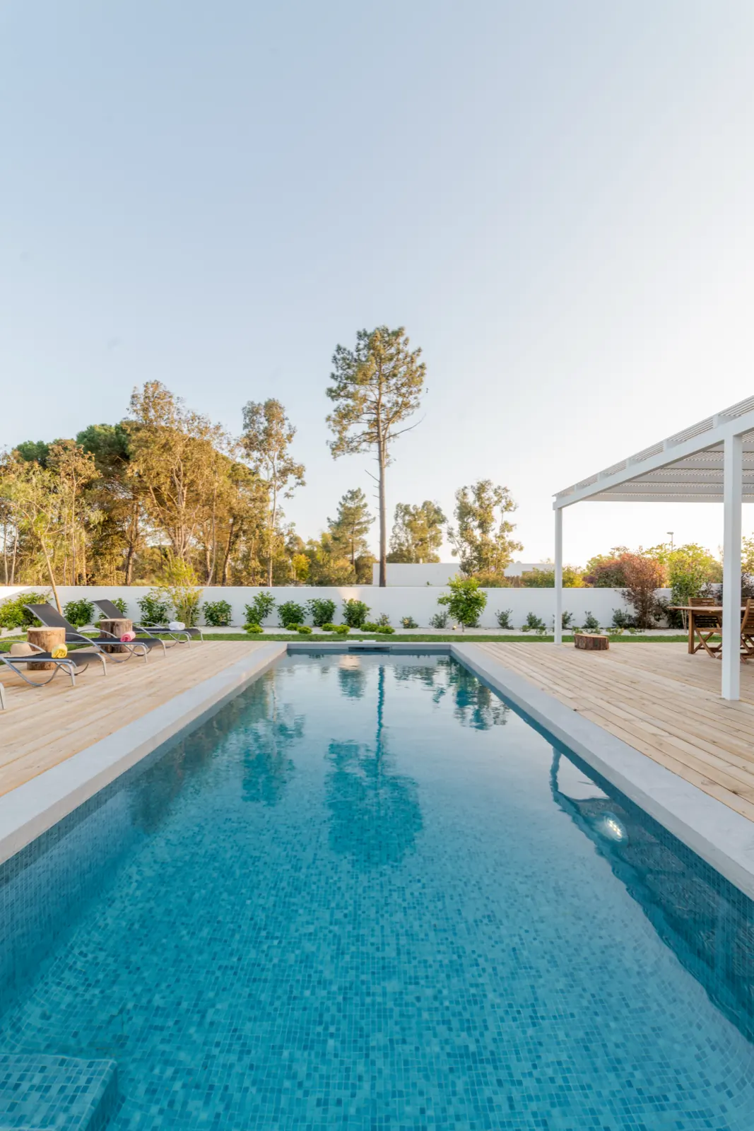 Long pool with a wood deck and pergola