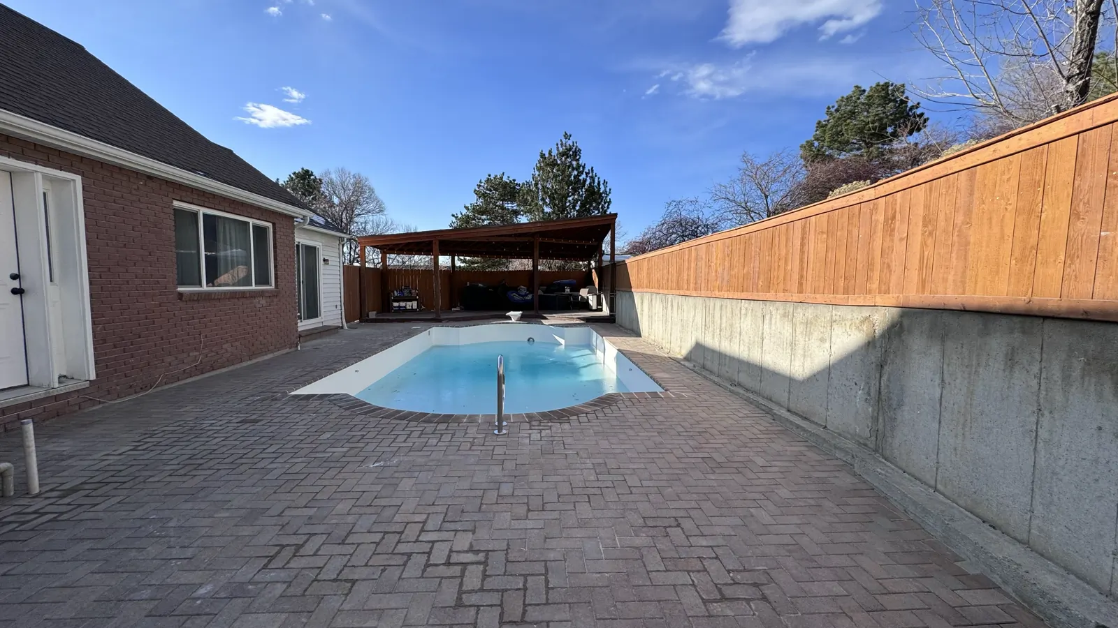 Finished backyard pool with a paver deck and covered pergola
